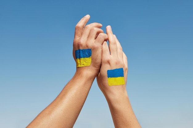 Female and male hands painted in ukraine flag colors holding stop the war