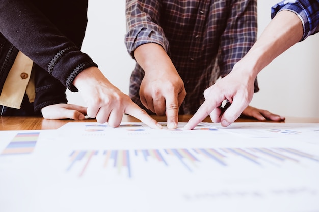 Photo female and male hands pointing at turnover graph while discussing it on wooden desk in office