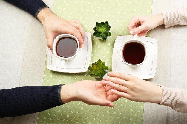 Female and male hands with cups of tea closeup