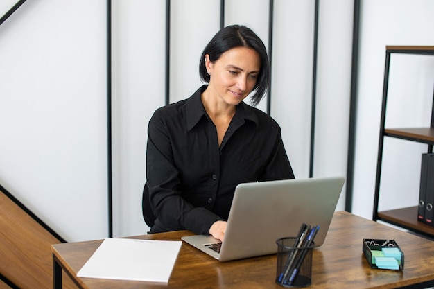 A female manager is sitting at a desk with a laptop