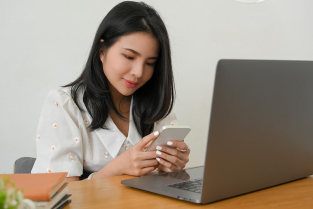 Female manager sitting at her office desk and chatting with someone on her smartphone