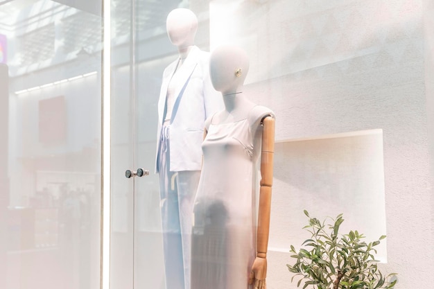 Female mannequins in elegant summer clothes in pastel colors in a boutique window Fashion style and beauty Front view