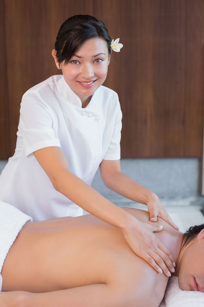 Female masseur massaging mans back at spa center