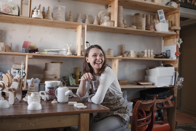 A female master sits at a workshop table among wooden toys small business concept