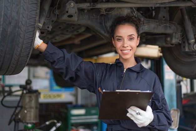 Female mechanic smiling and working repair maintenance a car in the auto service garage