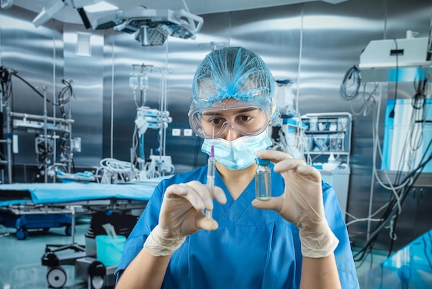 Female medical assistant wearing uniform holding syringe with antibiotic or covid19 vaccine dose in operating room at modert hospital