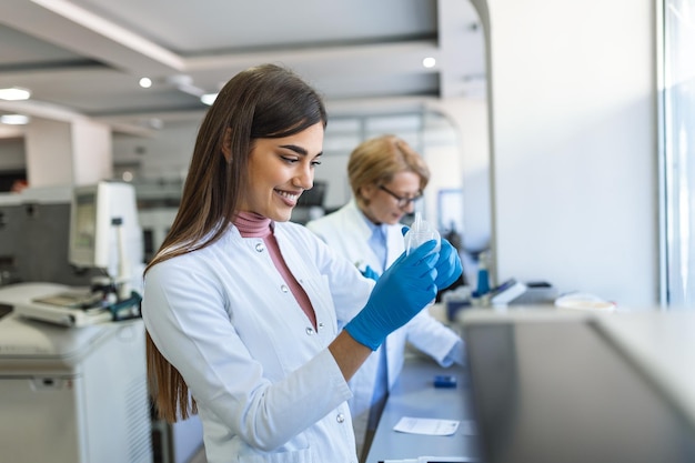 Female Medical Research Scientist Looks at Biological Samples Before Analysing it Under Digital Microscope in Applied Science Laboratory Lab Engineer in White Coat Working on Vaccine and Medicine