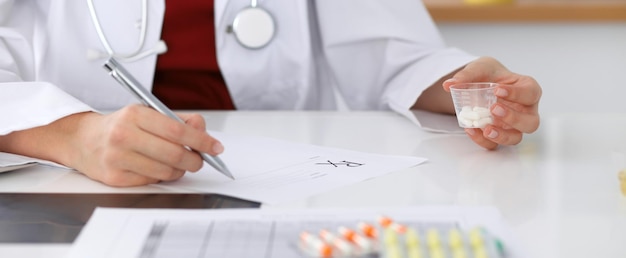 Photo female medicine doctor fills up  prescription form to patient closeup. panacea and life save, prescribe treatment, legal drug store, contraception concept