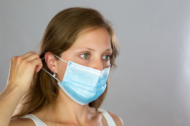 Female model in white shirt attaching surgical face mask