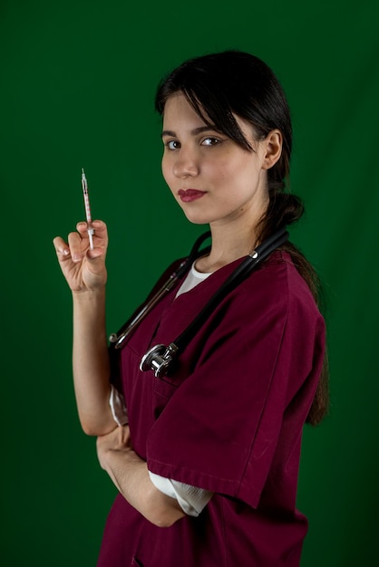 Female nurse in protective overalls holding vaccine and syringe isolated on background A female doctor with gloves and a mask prepares a vaccine in the hospital concept of medicine