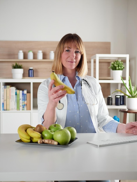 Female nutritionist holding a banana fruit in office studio