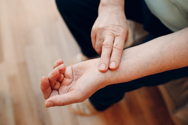 Female old hand measuring her own arm pulse. Elderly woman heart health