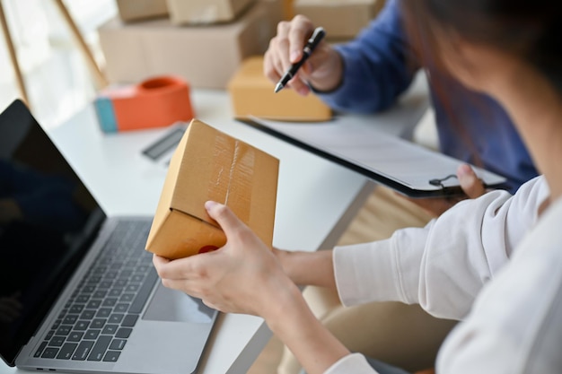 A female online seller checking orders and examining a shipping box before shipment