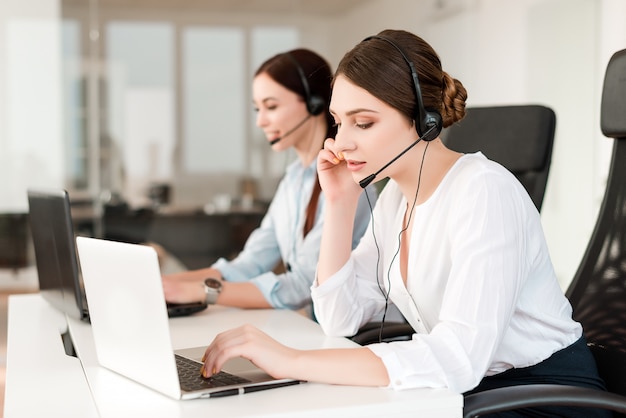 female operator in call center answers clients with headset and laptop in the tech support office