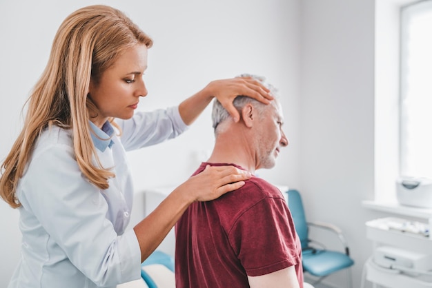 Female orthopedist examining patient's neck in hospital