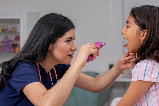 Female paediatrician checking a child's mouth in her office with a lamp