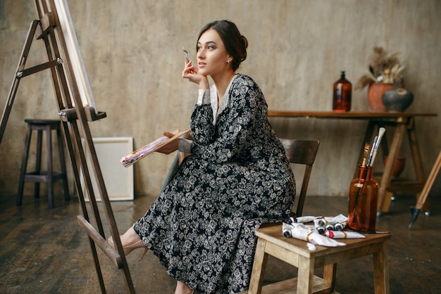 Female painter sitting at the easel in art studio