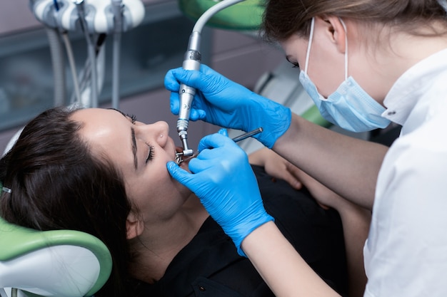 Female patient at the dentist drilling the tooth with a turbine and making dental fillings