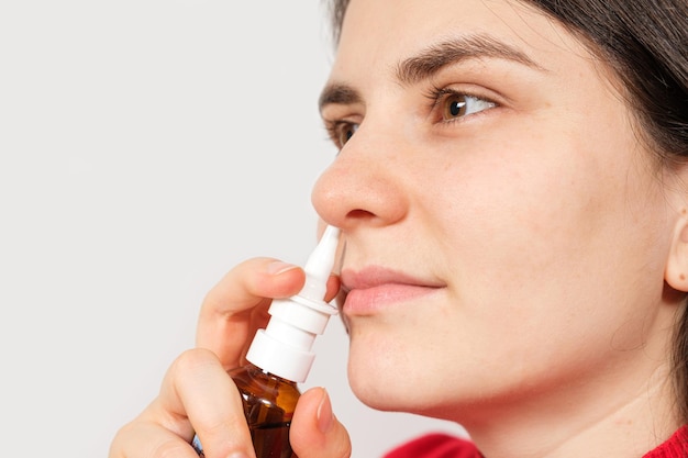 A female patient shoves a spray into the nose to treat rhinitis