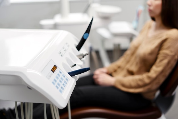 Female patient sits in a dental chair sterile clean dental instruments are in the foreground A patient in a dental office is treating his teeth treatment without pain