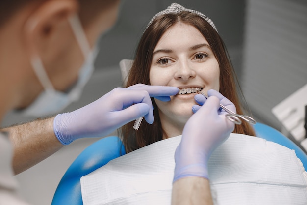 Female patient with braces examining dental inspection at dentist office. Woman in white clothes