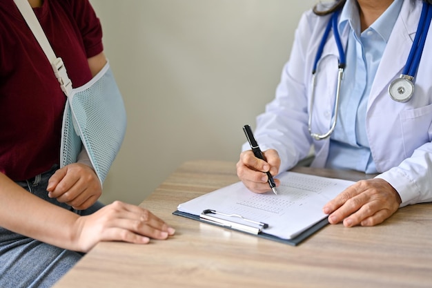 A female patient with a broken arm is being checked and diagnosed by an orthopedic doctor