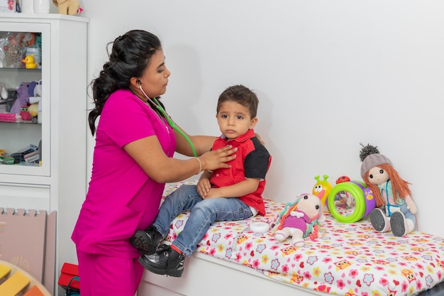 Female pediatrician doctor checking a child with her stethoscope in her office