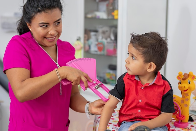 Female pediatrician doctor measuring the fat of a child with a caliper in her office