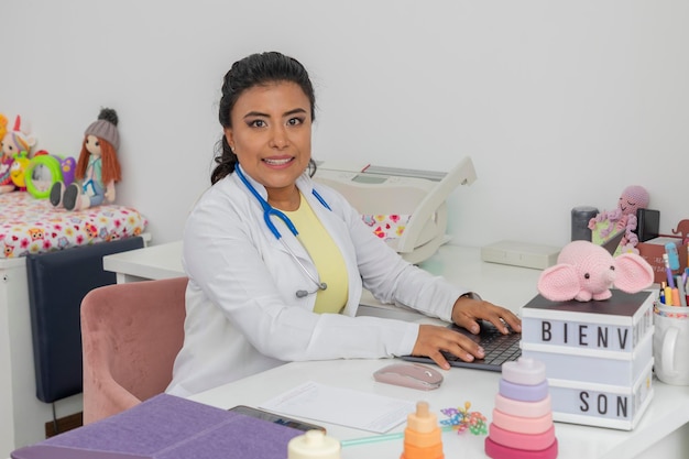 Female pediatrician doctor sitting at desk in her office looking at camera with copy space