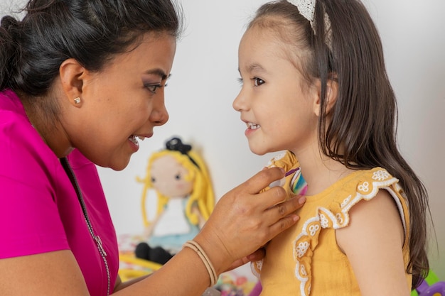 Female pediatrician placing a bandage on a girl who is in her medical office