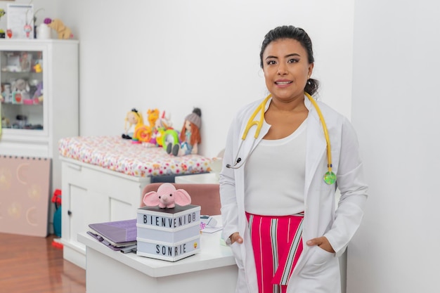 Female pediatrician standing in front of the desk in her medical office