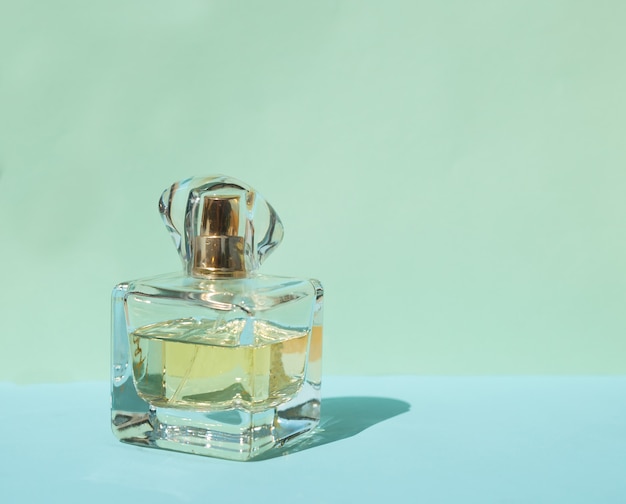 Female perfume bottle on a pastel blue background with crystal shadows