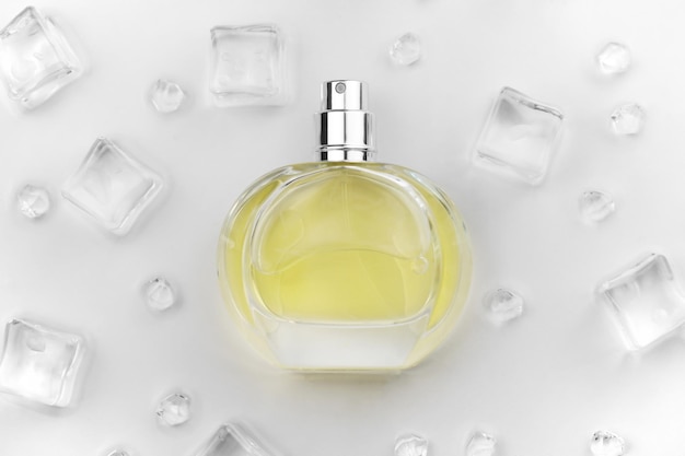 Female perfume yellow bottle Objective photograph of perfume bottle in ice cubes and water on white table View from above Mockup product photo concept of freshness