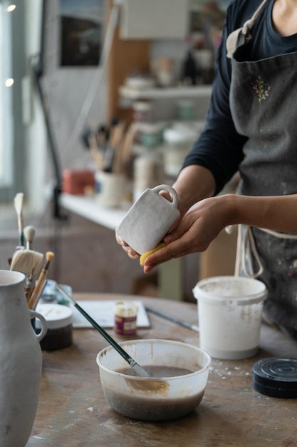 Female person enjoys working with handmade crockery taking courses of pottery craft in studio