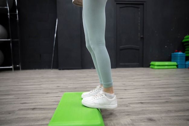 Photo female person stepping up on green aerobic platform during workout