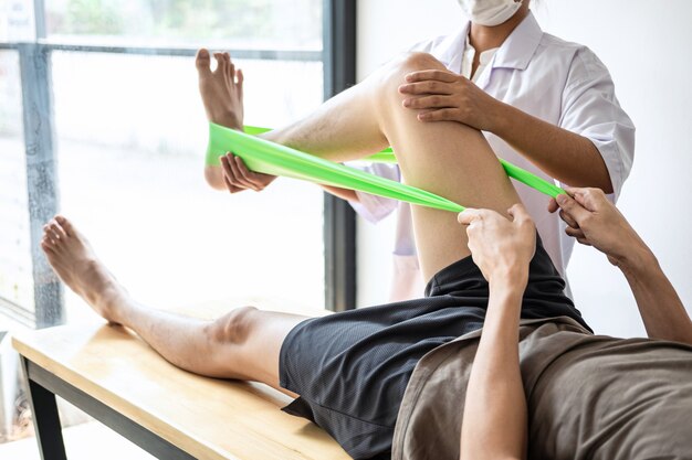 Female physiotherapist treating injured leg of male patient