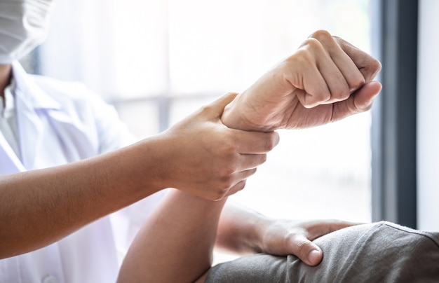 Female Physiotherapist working examining treating injured arm of athlete male patient, stretching and exercise, Doing the Rehabilitation therapy pain in clinic.