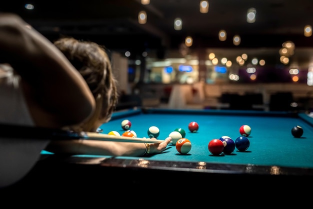 Female player playing pool and aiming the billiard ball with cue