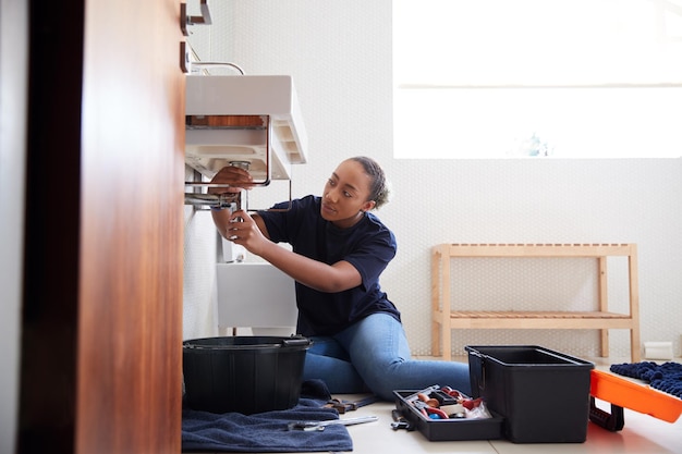 Photo female plumber working to fix leaking sink in home bathroom