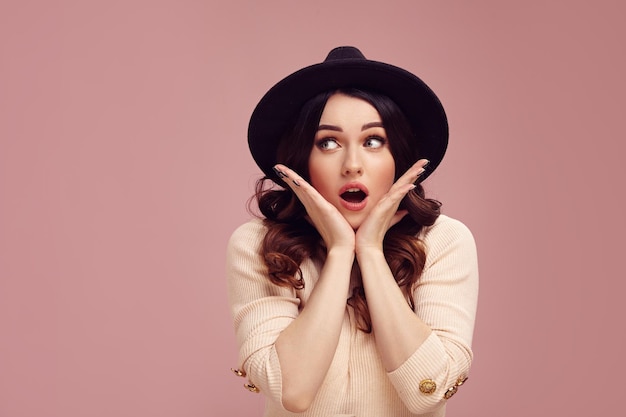 Female portrait of astonished woman putting her hands to the cheeks expresses amazement