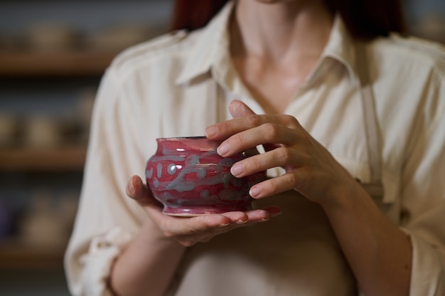 Female potter holding newlymade pots in hands