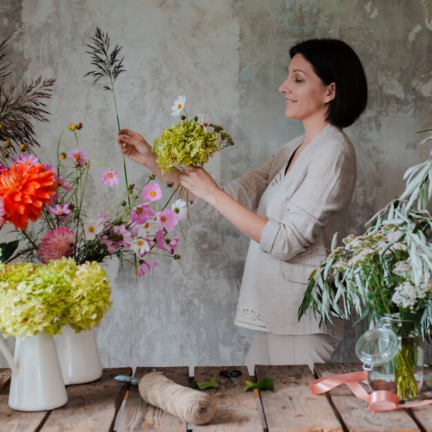 Photo female professional florist prepares the arrangement of wild flowers.