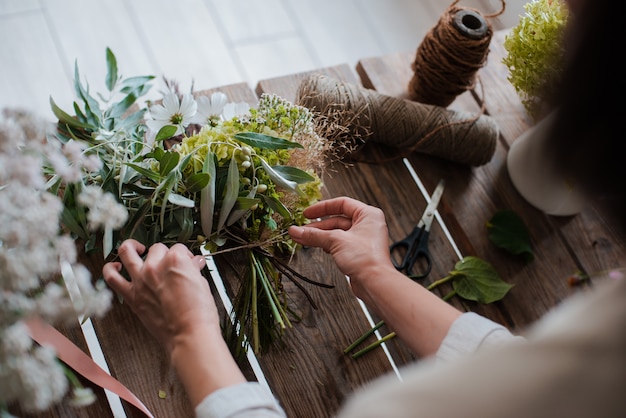 Female professional florist prepares the arrangement of wild flowers.