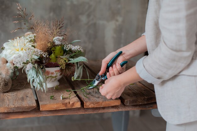 Photo female professional florist prepares the arrangement of wild flowers.