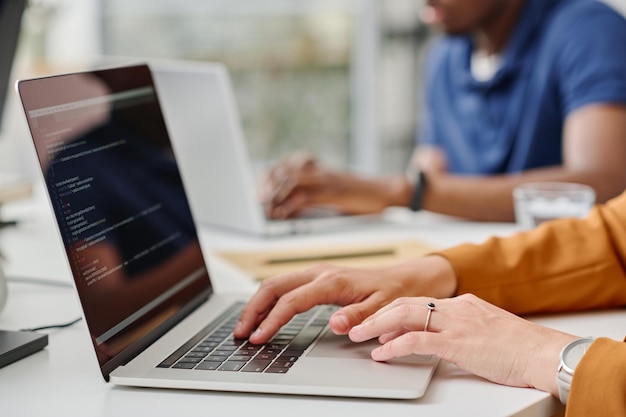 Female programmer typing codes on laptop