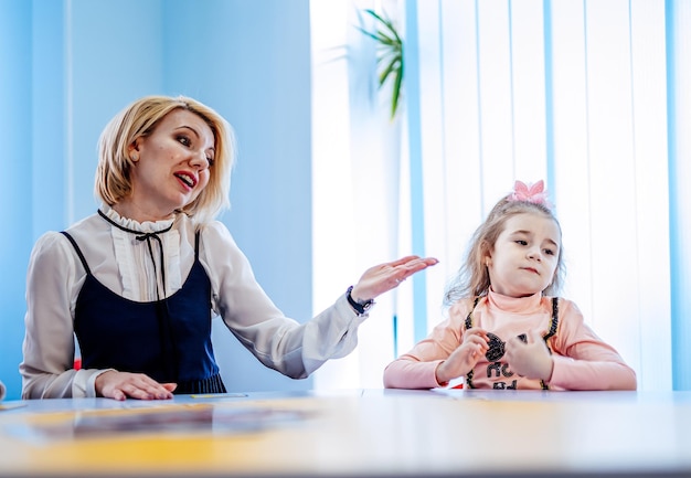 Female psychologist with cute little girl during play therapy