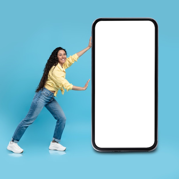 Female Pushing Cellphone With Large Empty Screen On Blue Background