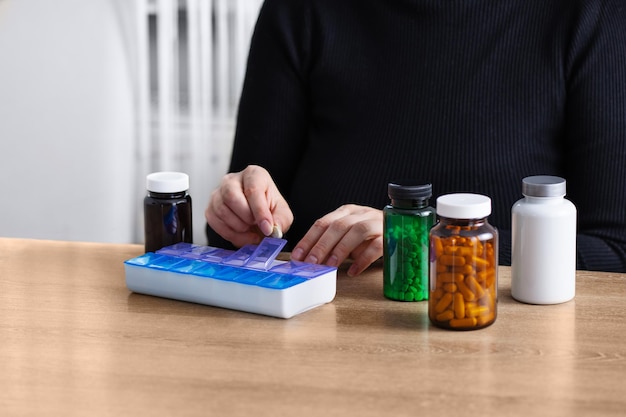 Female putting prescription pills and vitamins in a daily pill box organizer