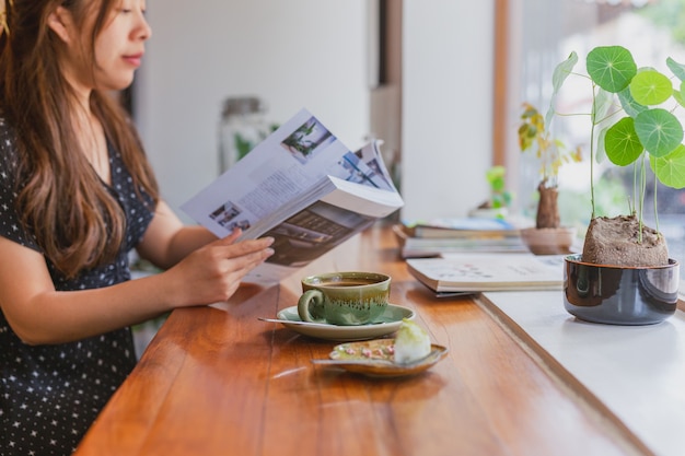 Female reading a magazine and drink coffee in cafe.