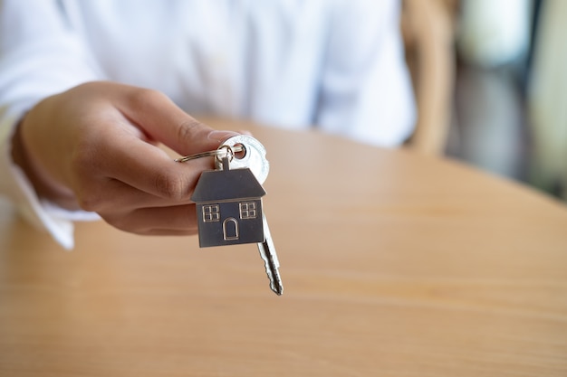 Female real estate agent hand holding house key, Real estate concept.